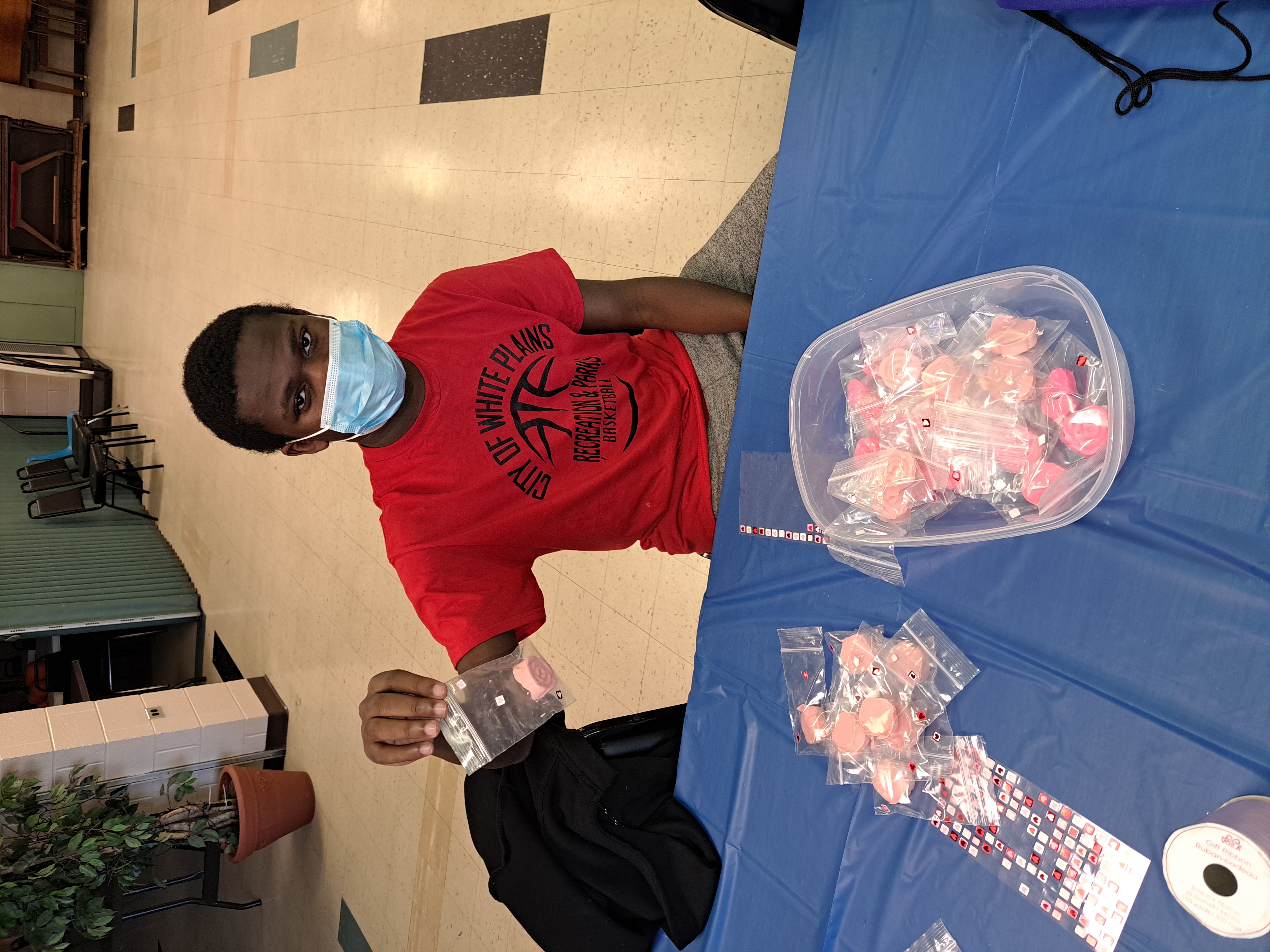 A student sits at a table making goody bags