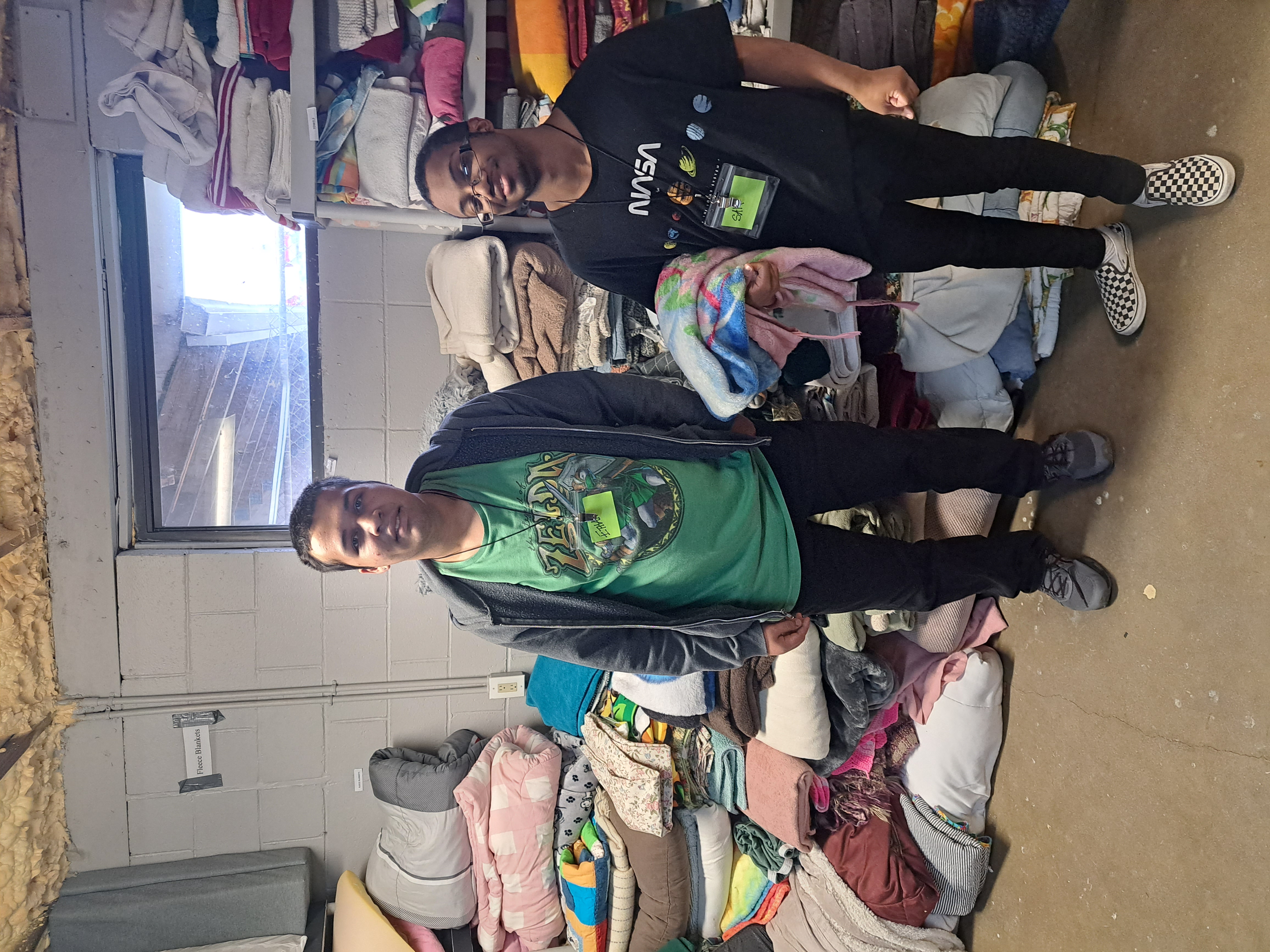 Students pose in front of piles of clothing at good will