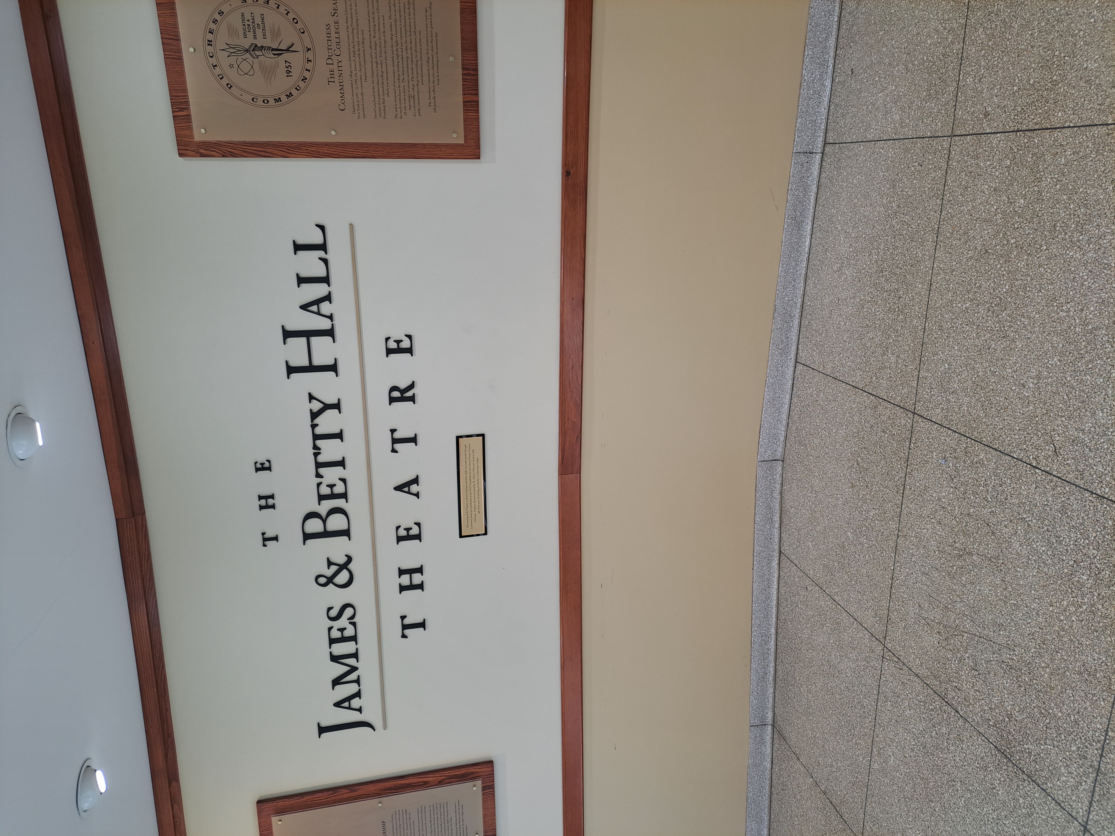 A photo of the wall inside a college that says "the james and betty hall theater"