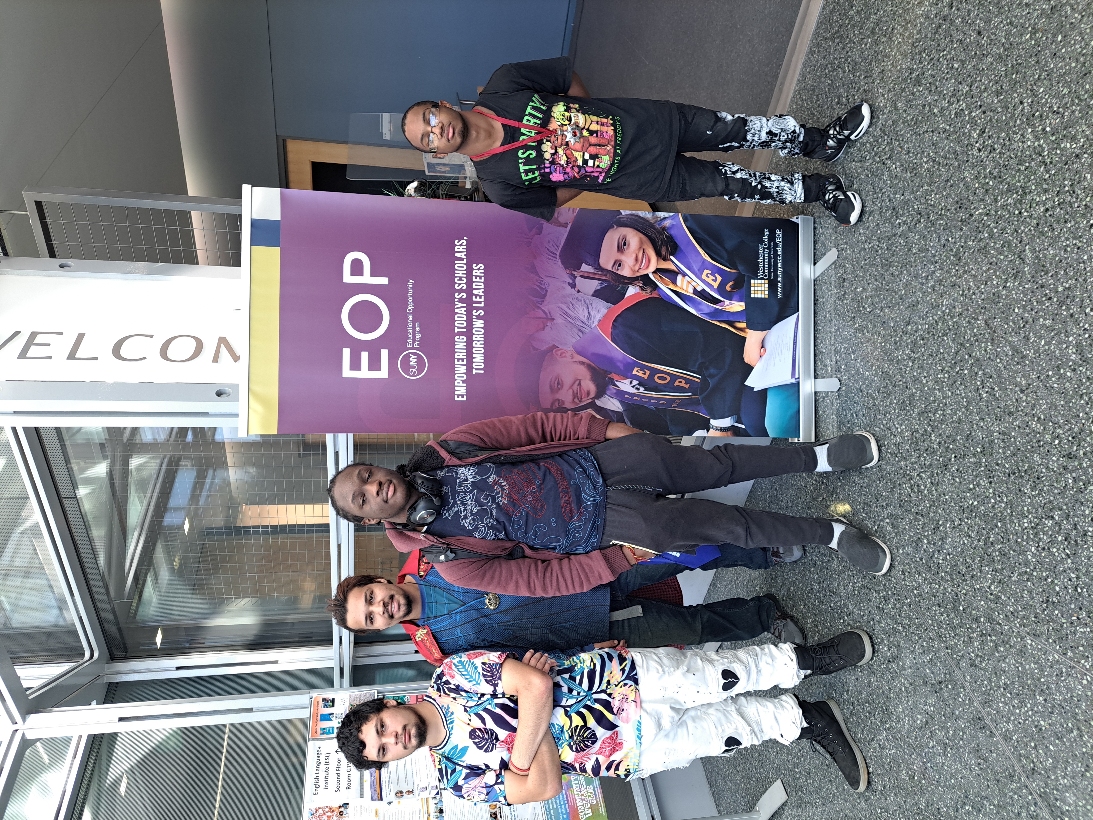 Students pose in front of a sign at westchester community college that says "EOP empowering todays scholars, tomorrows leaders"