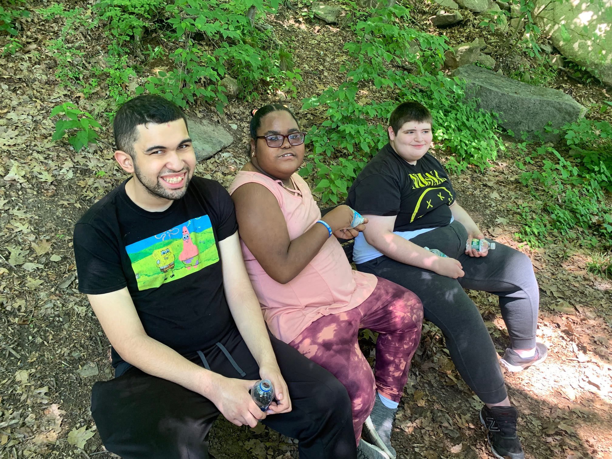 three students sit outside in the summer in the shade at bear mountain park