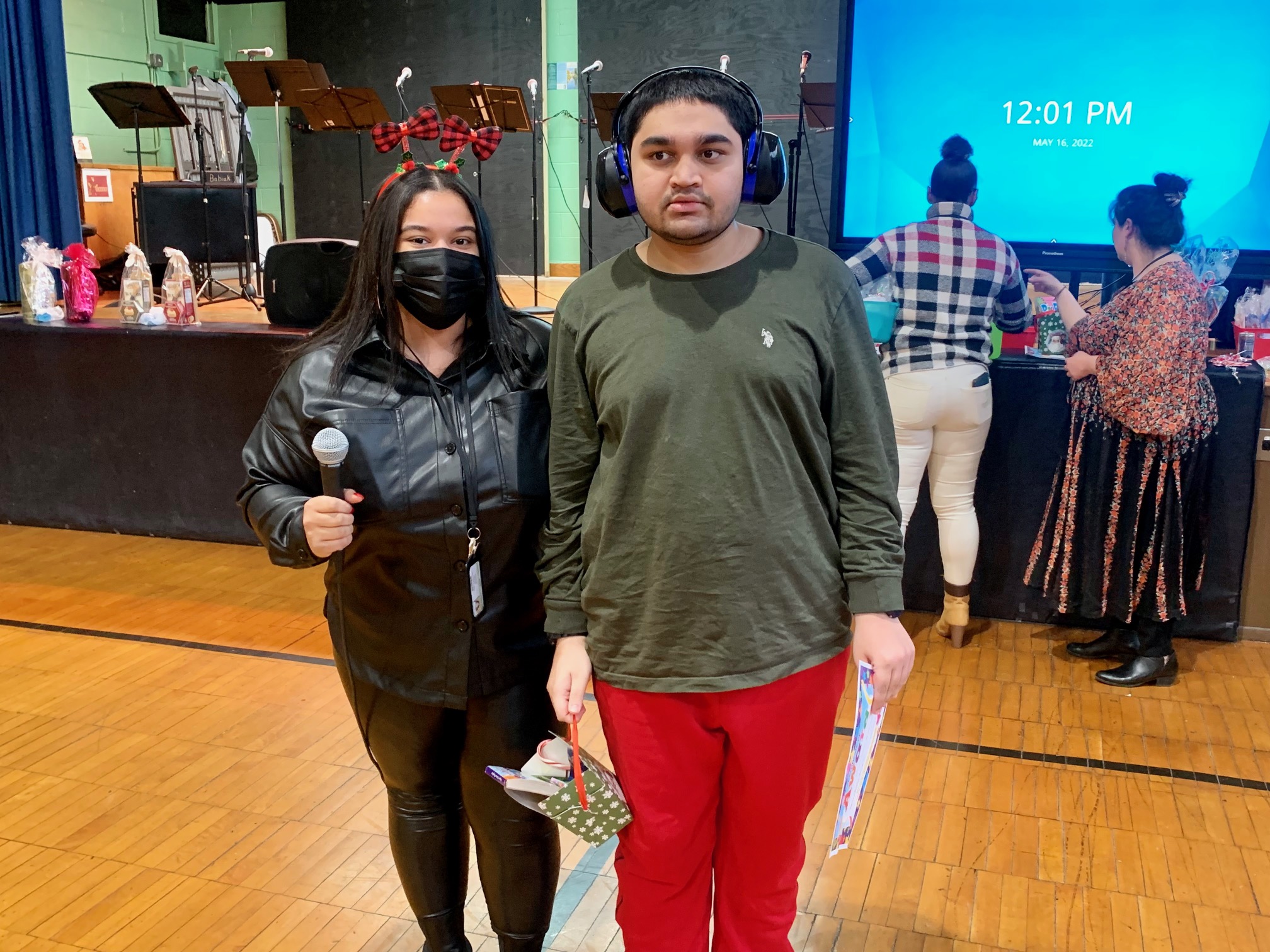 A classroom aide poses for a photo with a student in the gym. The student holds a prize he won