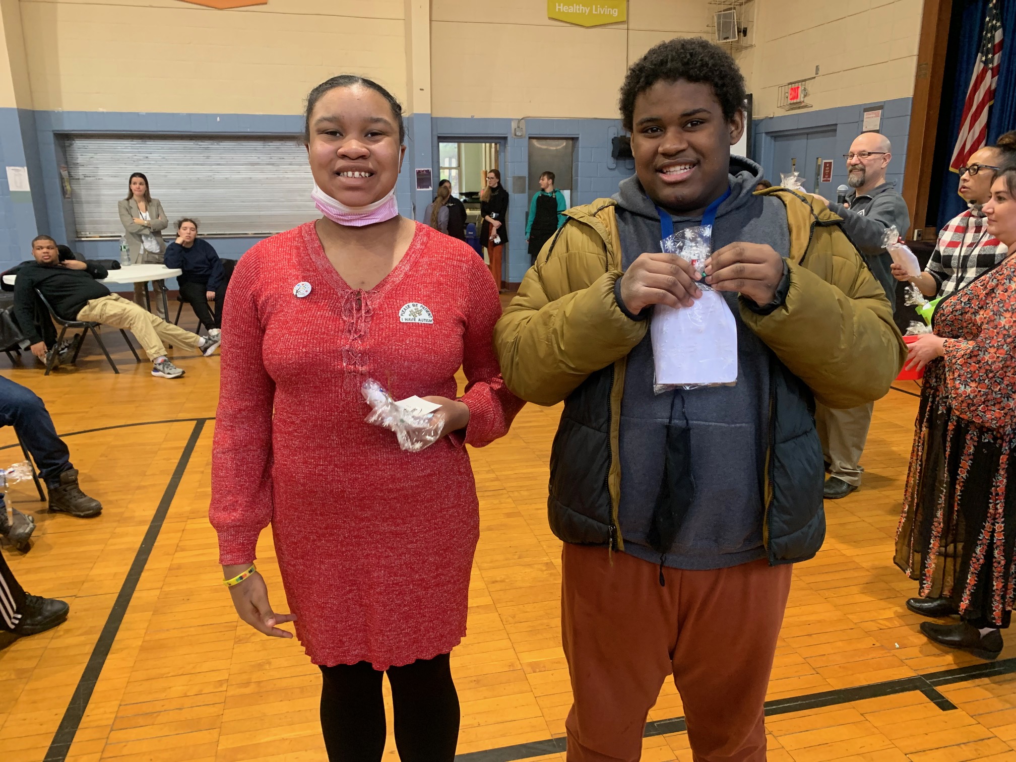 Two care academy students pose for a photo together in the gym holding prizes