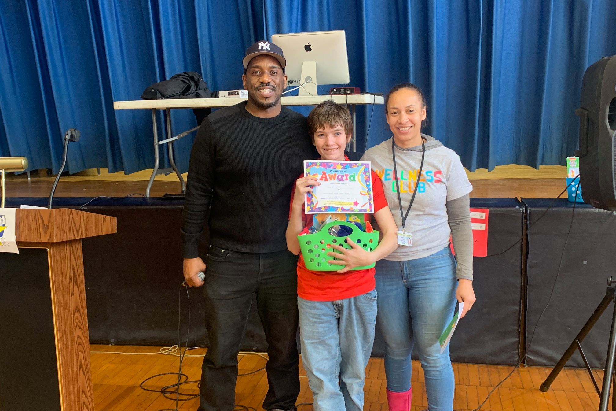 Mr. Bennett and Ms. Lacasse pose with a student who is standing in the middle holding his award and PBIS certificate for healthy living