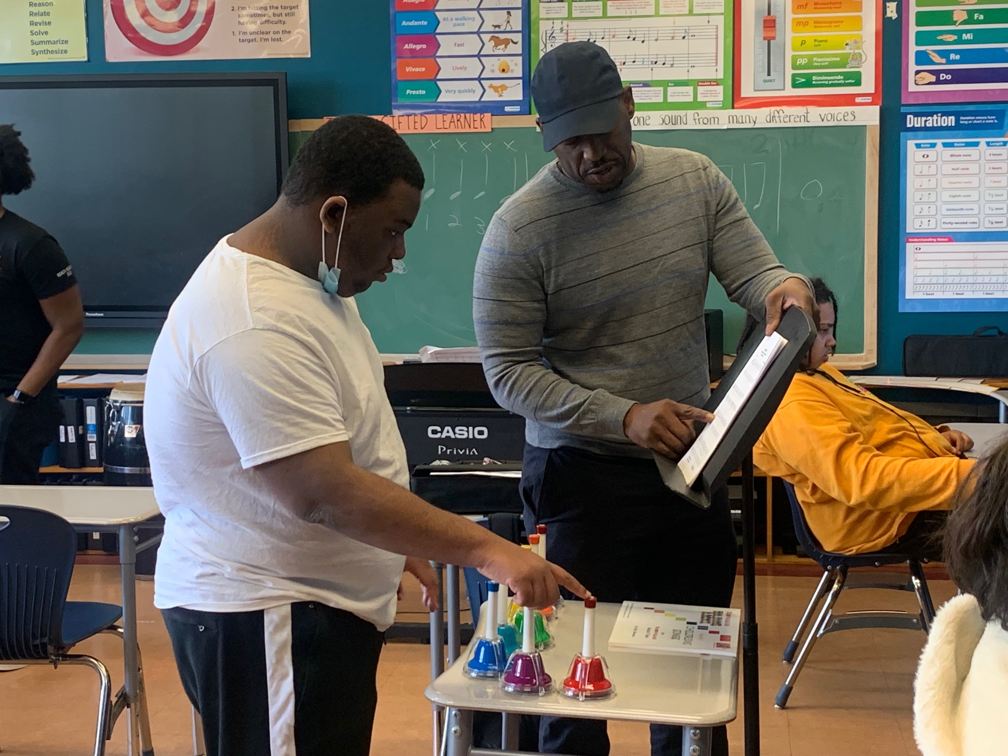 Mr. Bennett the music teacher assists a student in class with playing a set of bells