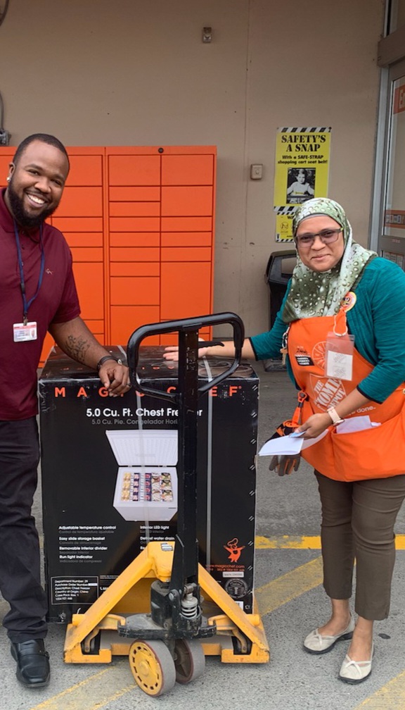 teacher and home depot staff in an orange apron standing next to donated item
