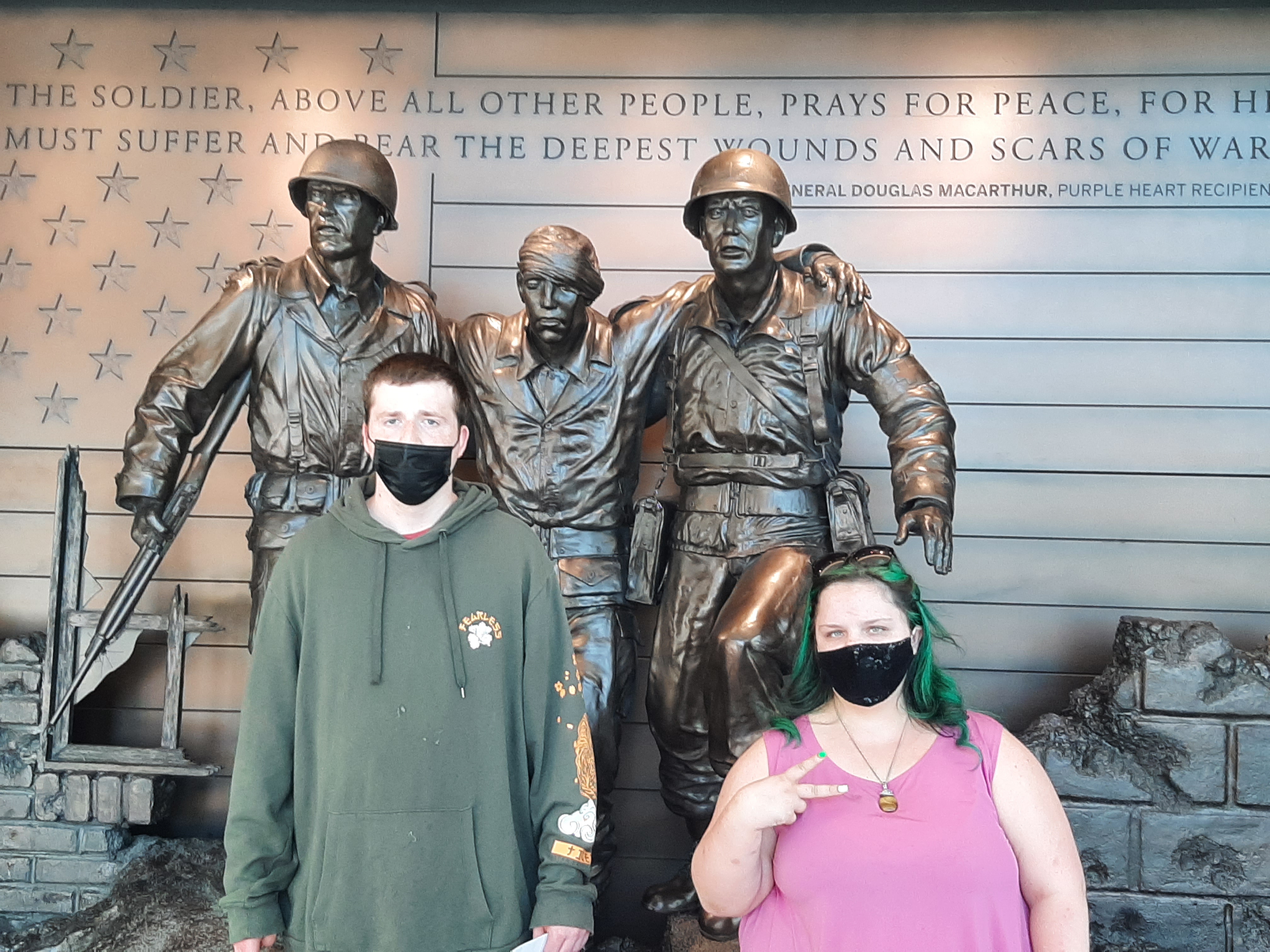 Students standing for a photo in front of memorial statue