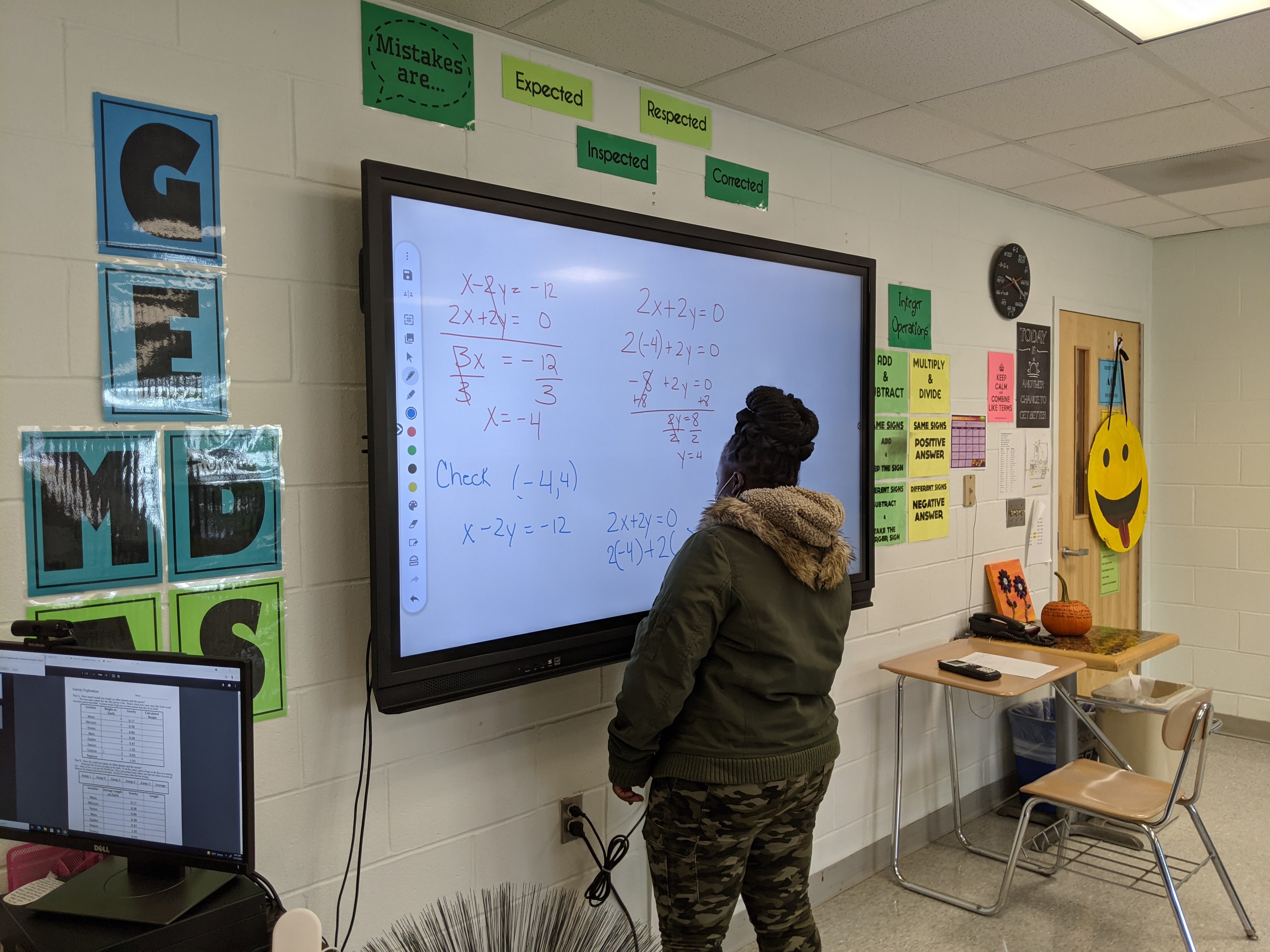 student solving math problem on interactive whiteboard in classroom