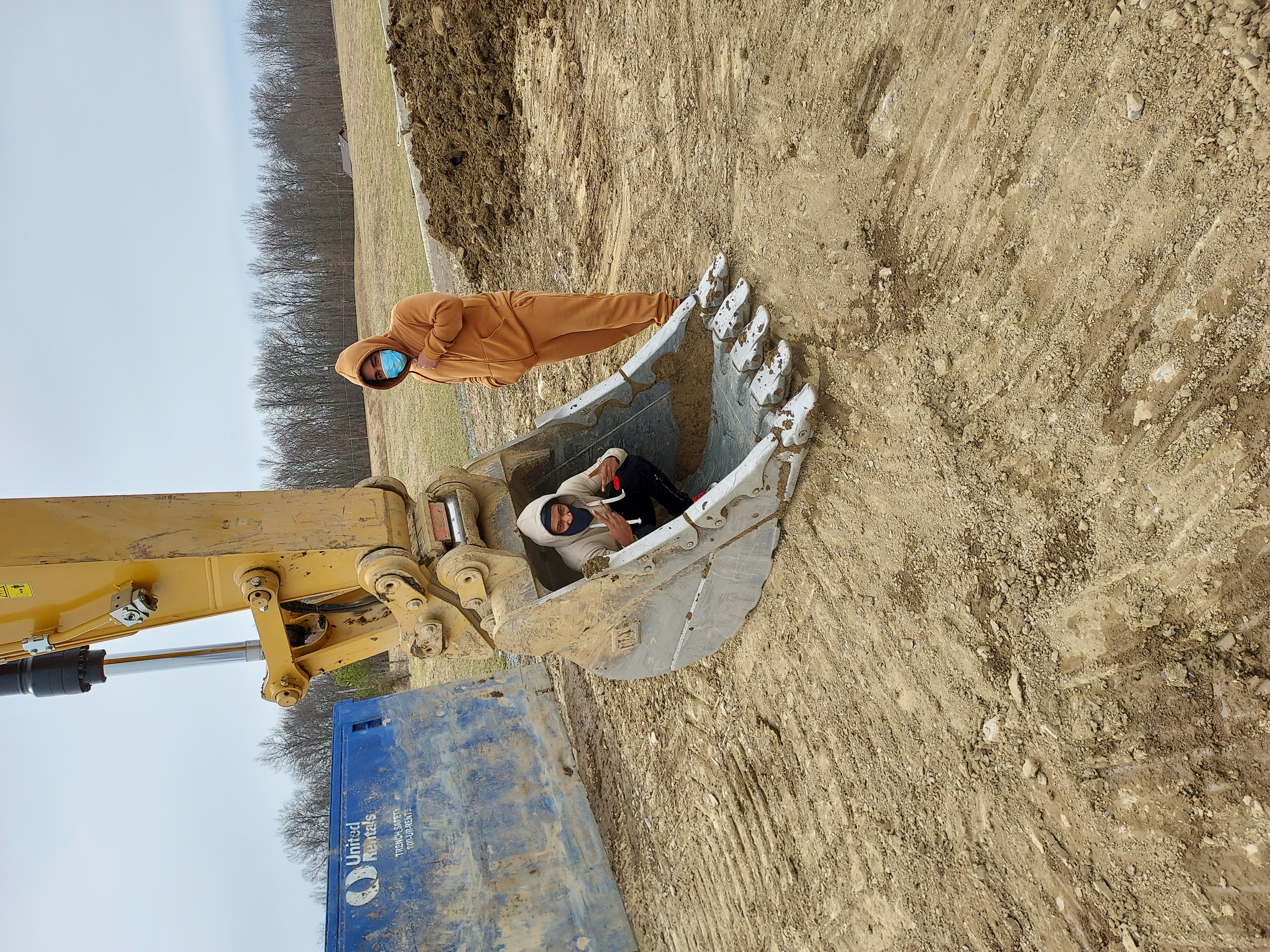 students standing next to construction vehicle