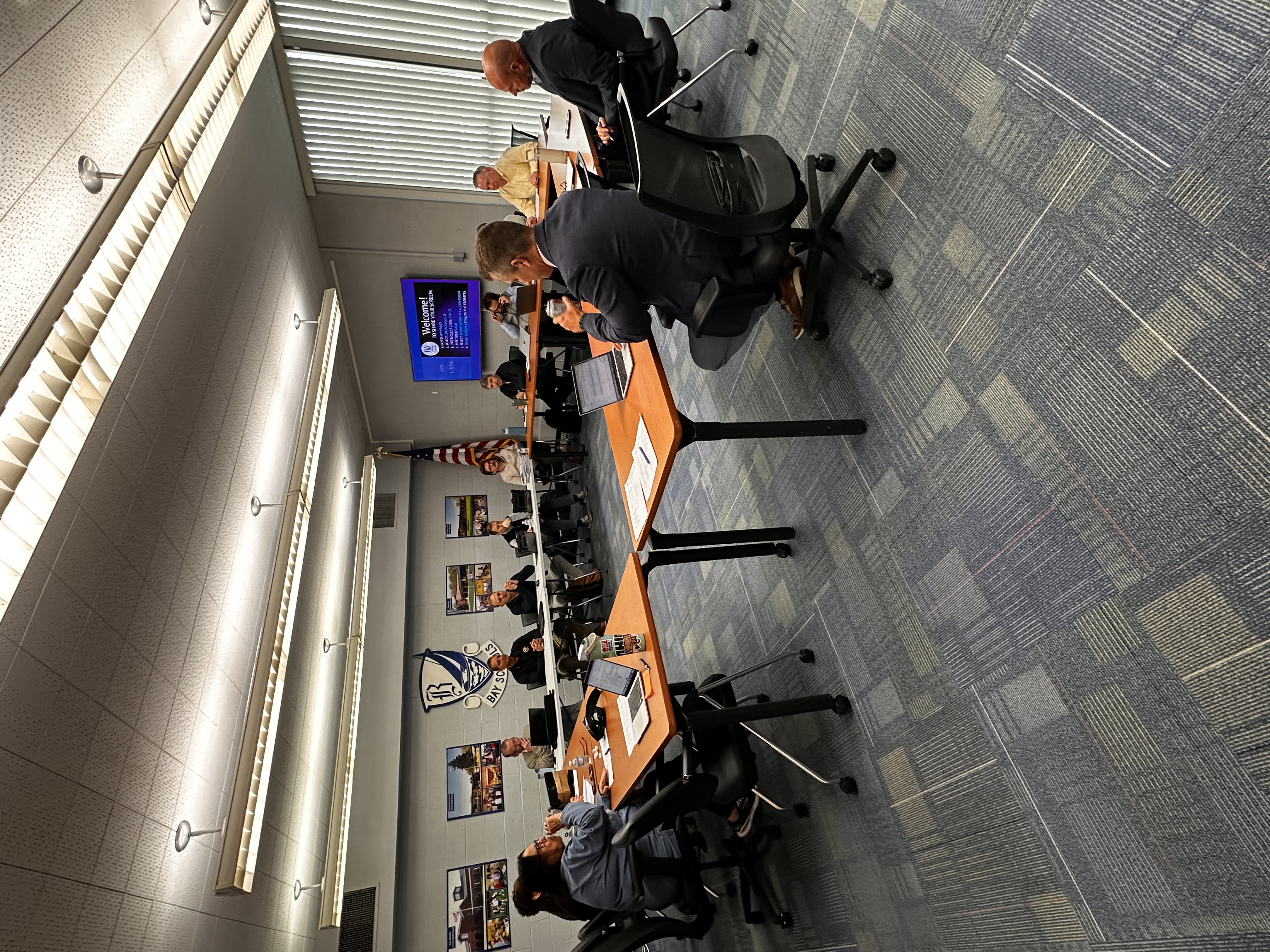 Facilities Core Team meeting photo from May 6, 2026 which includes team members seated at multiple tables of 14 people.
