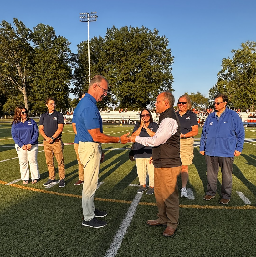 A photo of Supt. Scot Prebles receiving the Command Coin on the 50-yard line of Bay High Memorial Stadium before a football game.