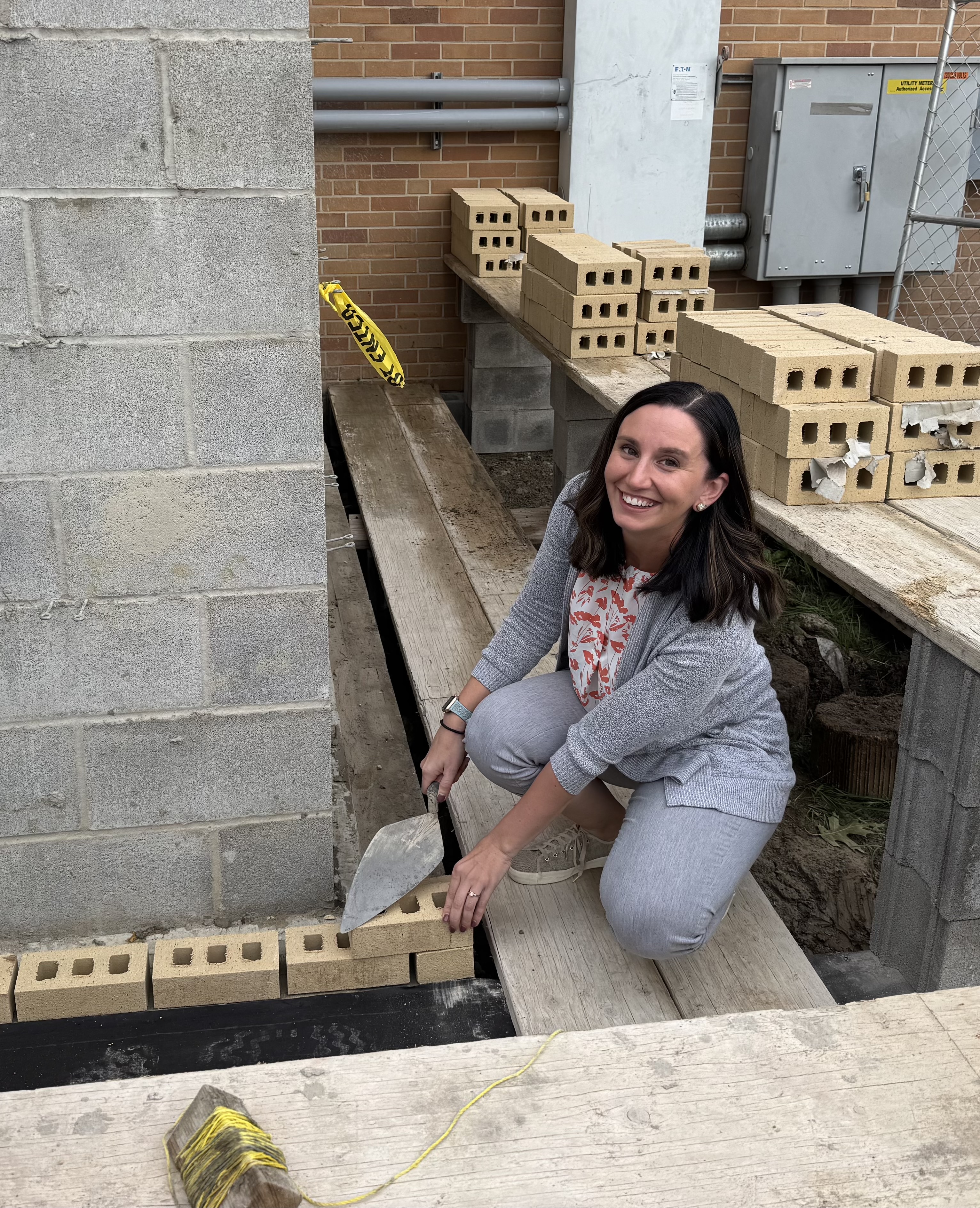Glenview director Alexa Davey lays the first brick of the new Glenview Center one-story foundation.