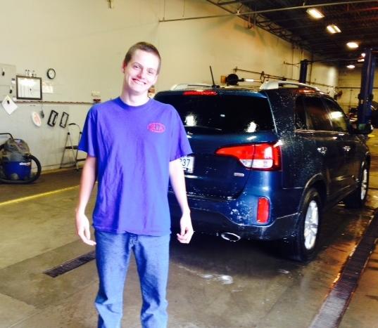 Student standing in front of a van in an auto shop