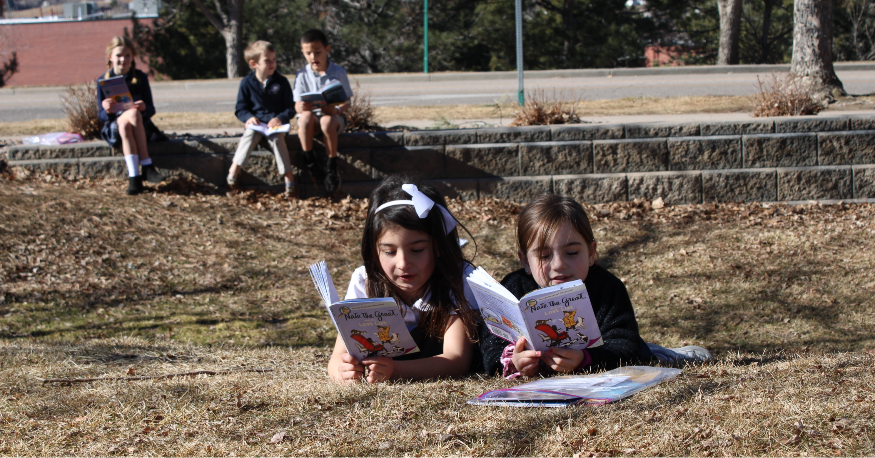 Girls reading on front lawn