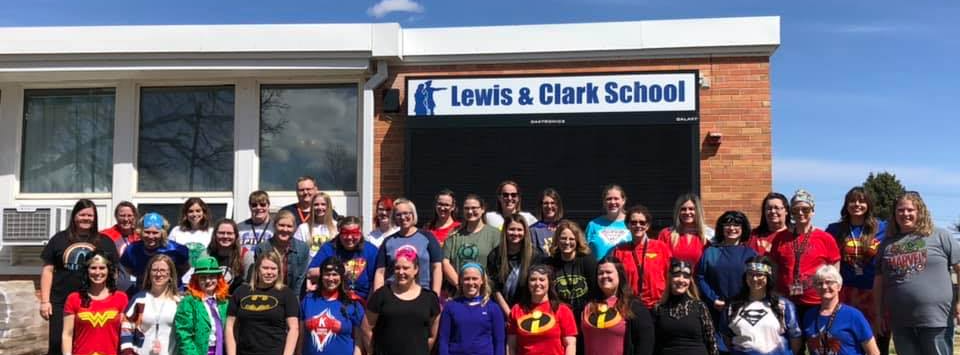 Lewis and Clark staff members dressed as superheroes taking group picture in front of the school building