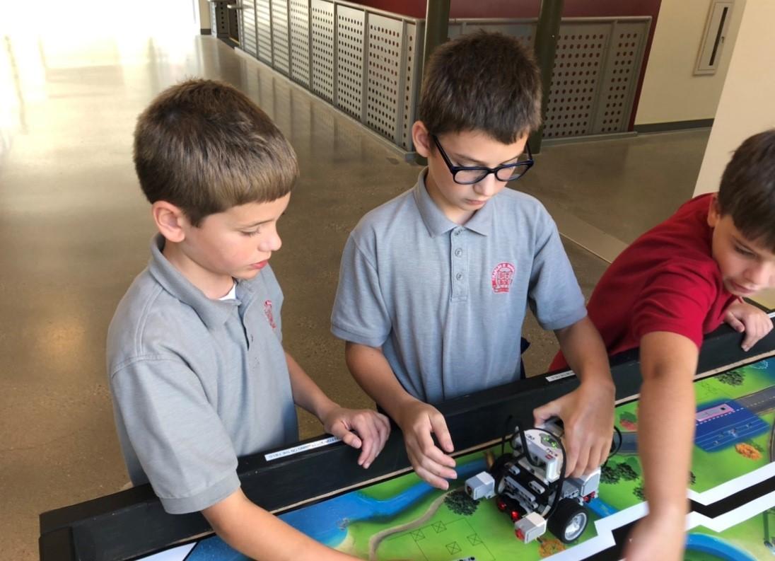 Younger FLL students working with robot