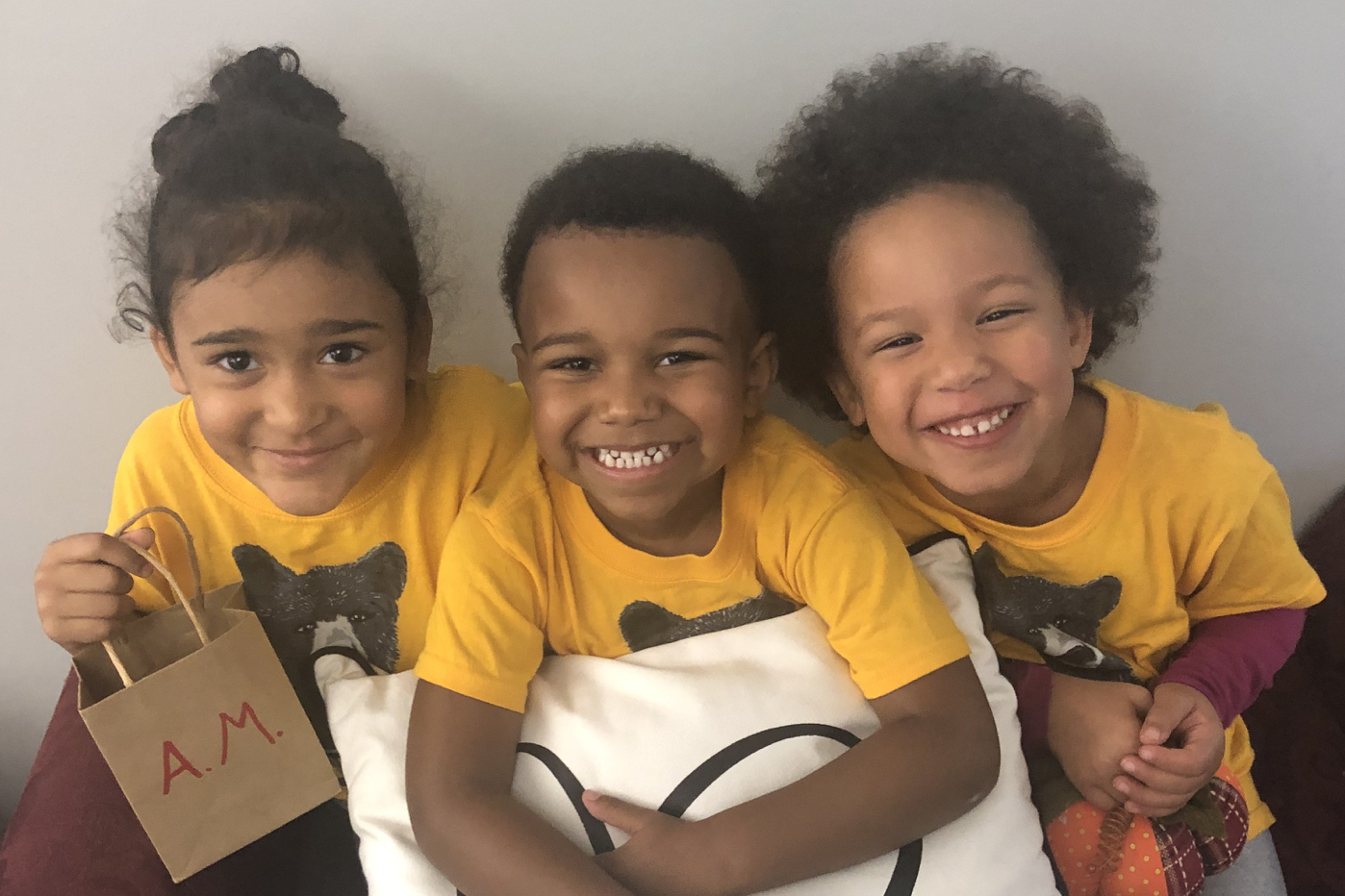 Three children in yellow t-shirts smiling at the camera