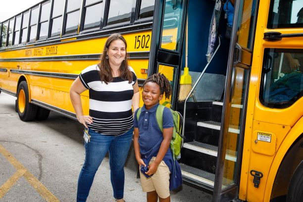 student and teacher in front of school bus