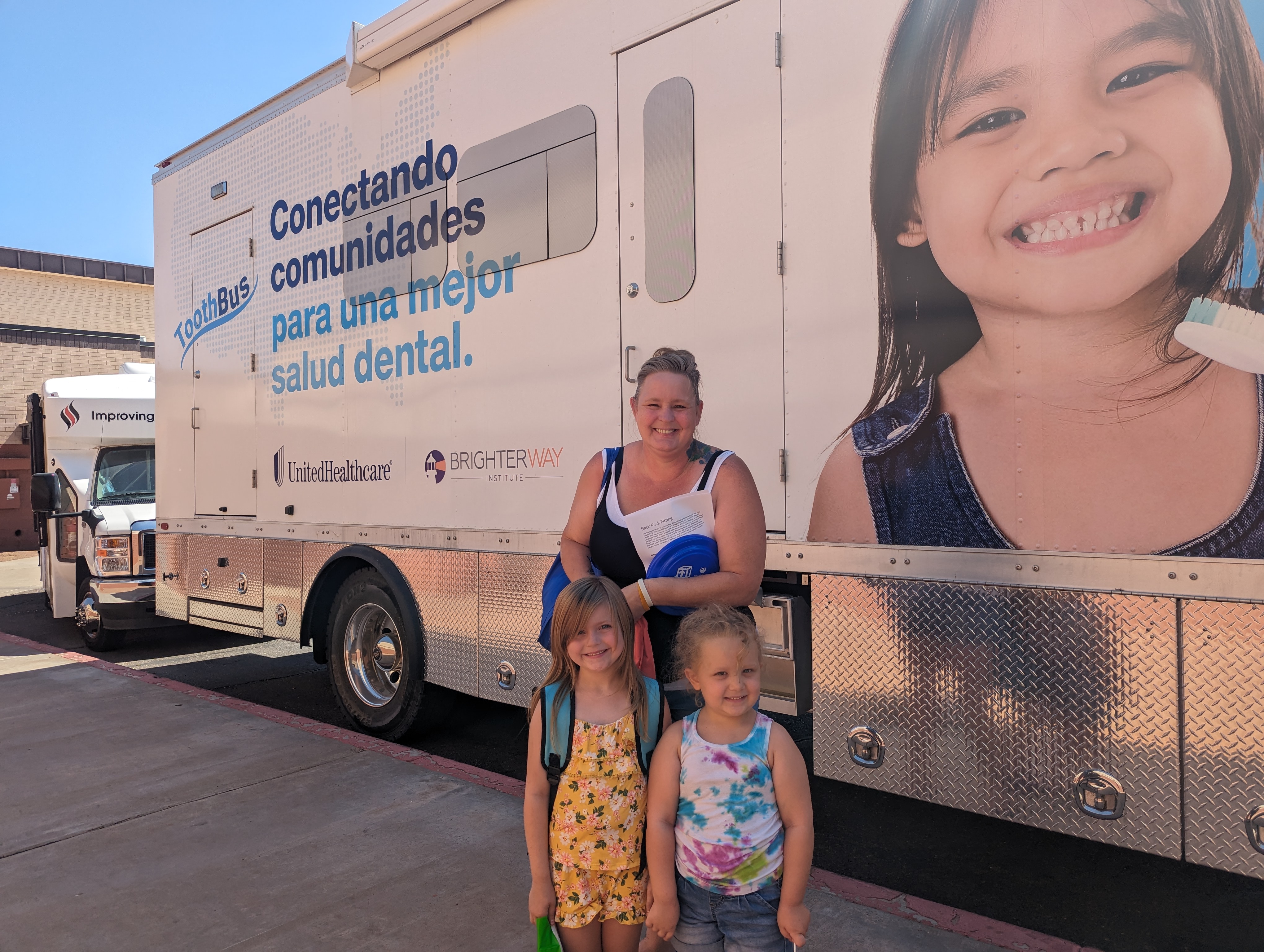 Family and children standing in front of the dental truck during the back to school health fair