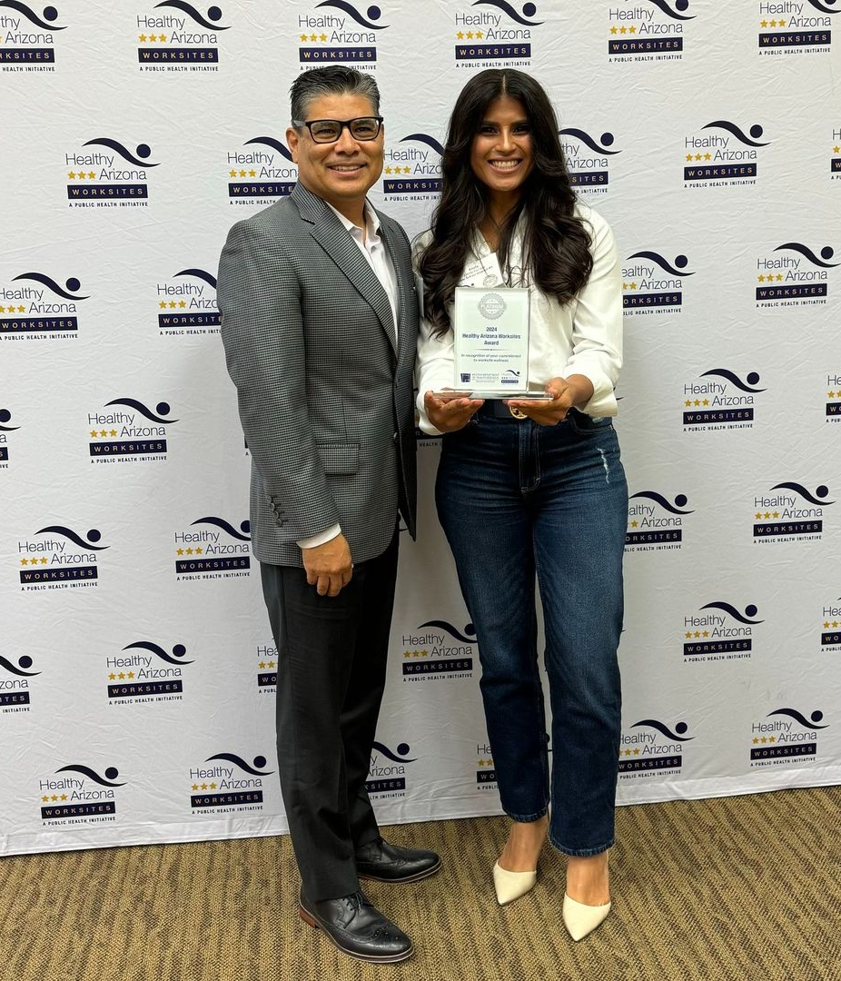 ISD superintendent and community health and safety specialist holding award while posing for photo in front of a backdrop