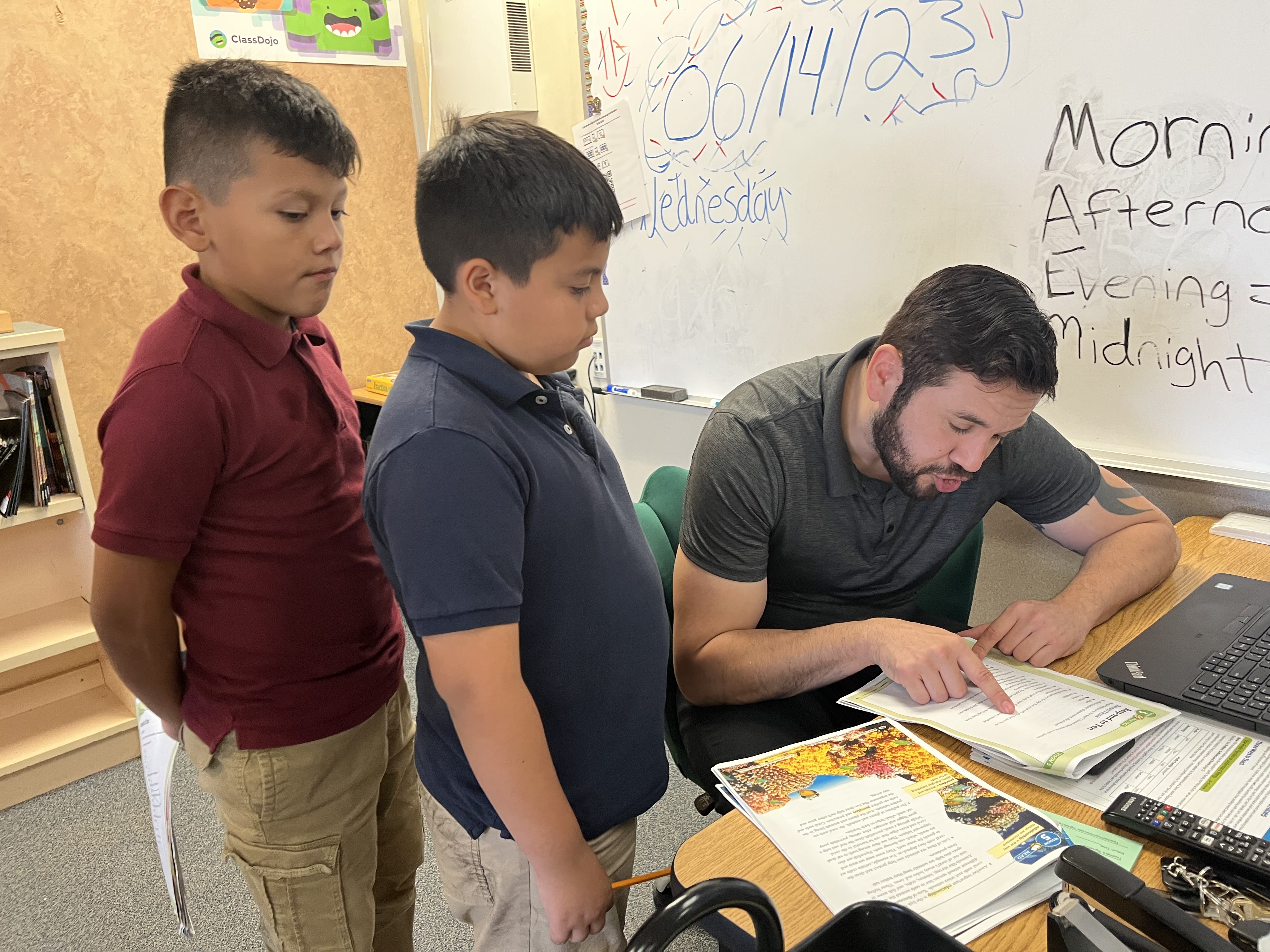 Teacher helping 2 students at his desk