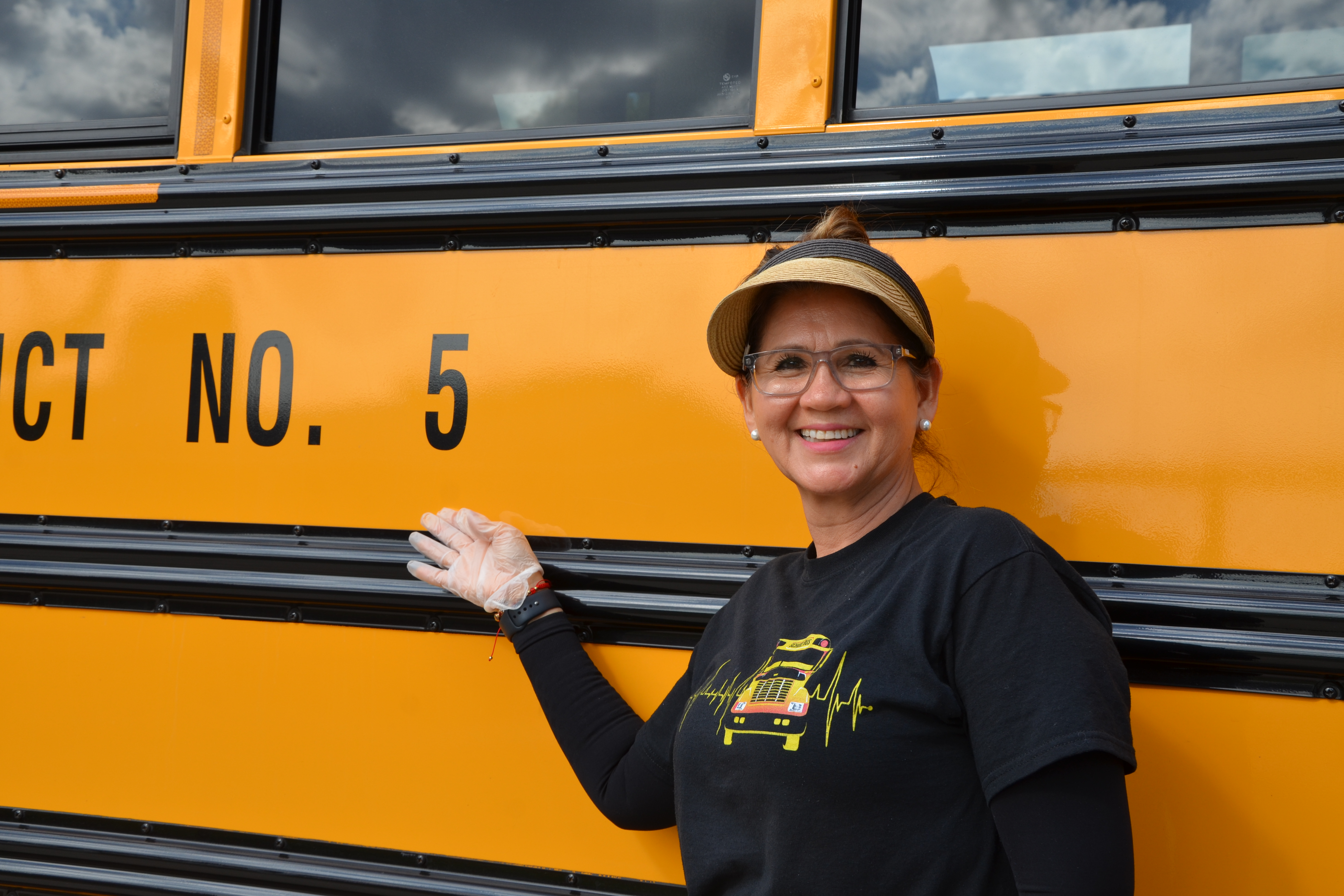 ISD staff member smiling for photo in front of yellow school bus