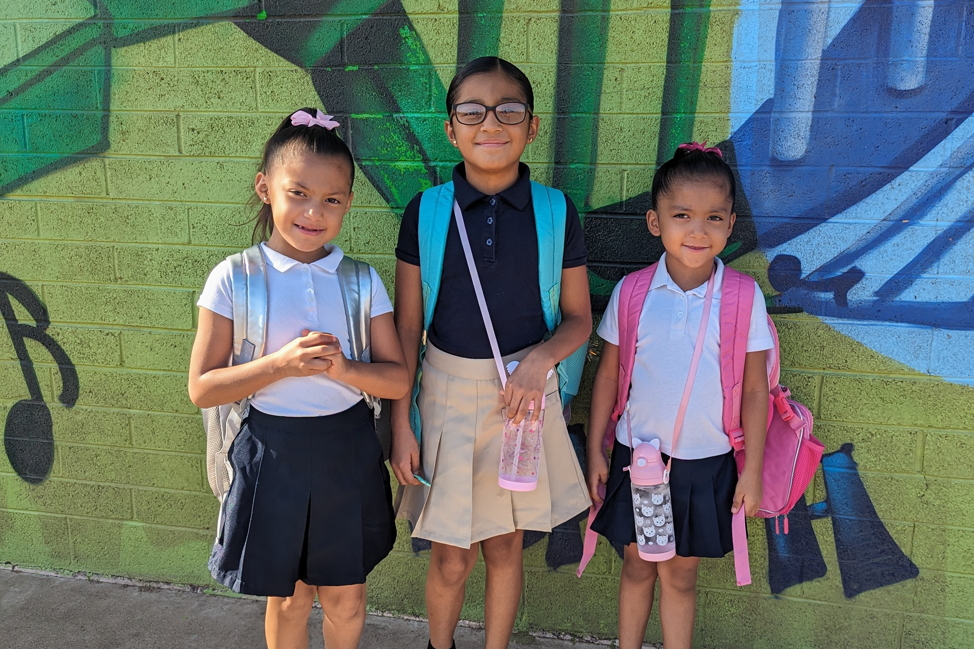 3 students posing with backpacks on the first day of school