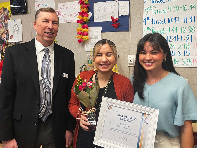 3 people smiling for photo. 2 of the people are ISD employees. The ISD employee in the middle is holding a certificate for an award. The additional ISD employee is on the right. A representative from law firm who is presenting the award is also in the photo to the left. 