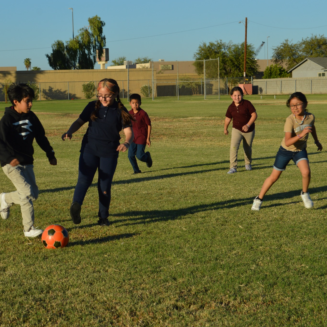 elementary students outdoors playing soccer in the field