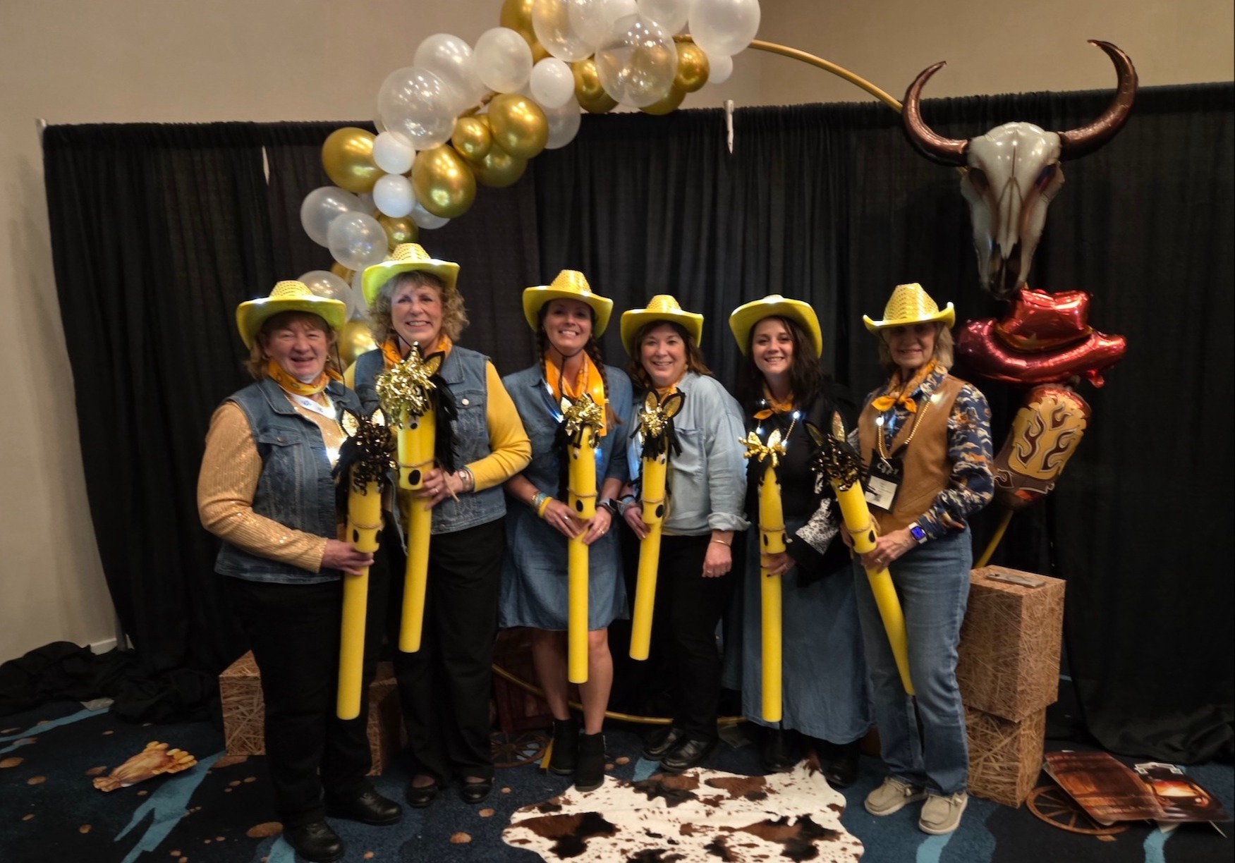 PAT staff at conference of the young years dressed up as cowboys with pool noodle stick horses