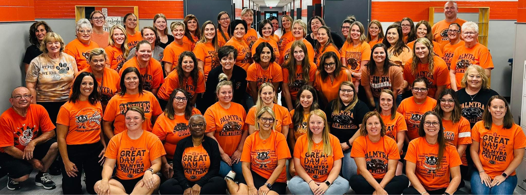 PES staff photo, where all staff are wearing orange shirts 08-2025