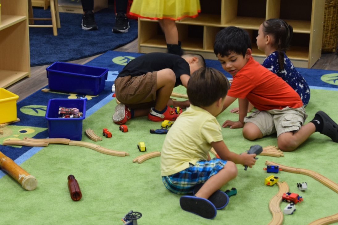 Enroll Today -  Isaac preschool students playing on carpet 