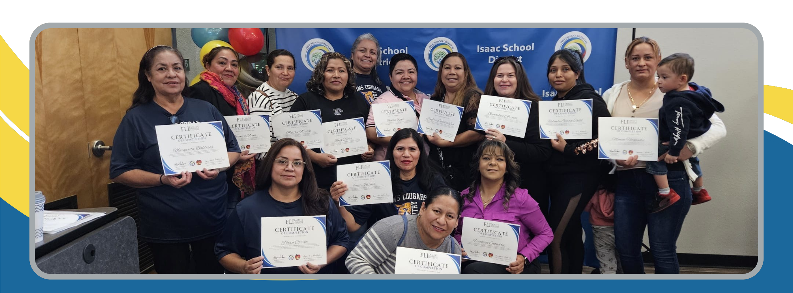 Group photo of middle school parents who proudly display a certificate of achievement in front of a school district blue backdrop decorated with yellow, red, black, and blue balloons