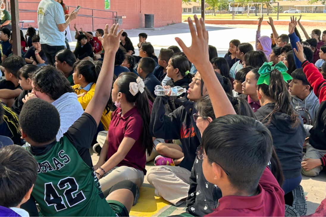 Enroll Today - students participating in rally  with hands waving in the air