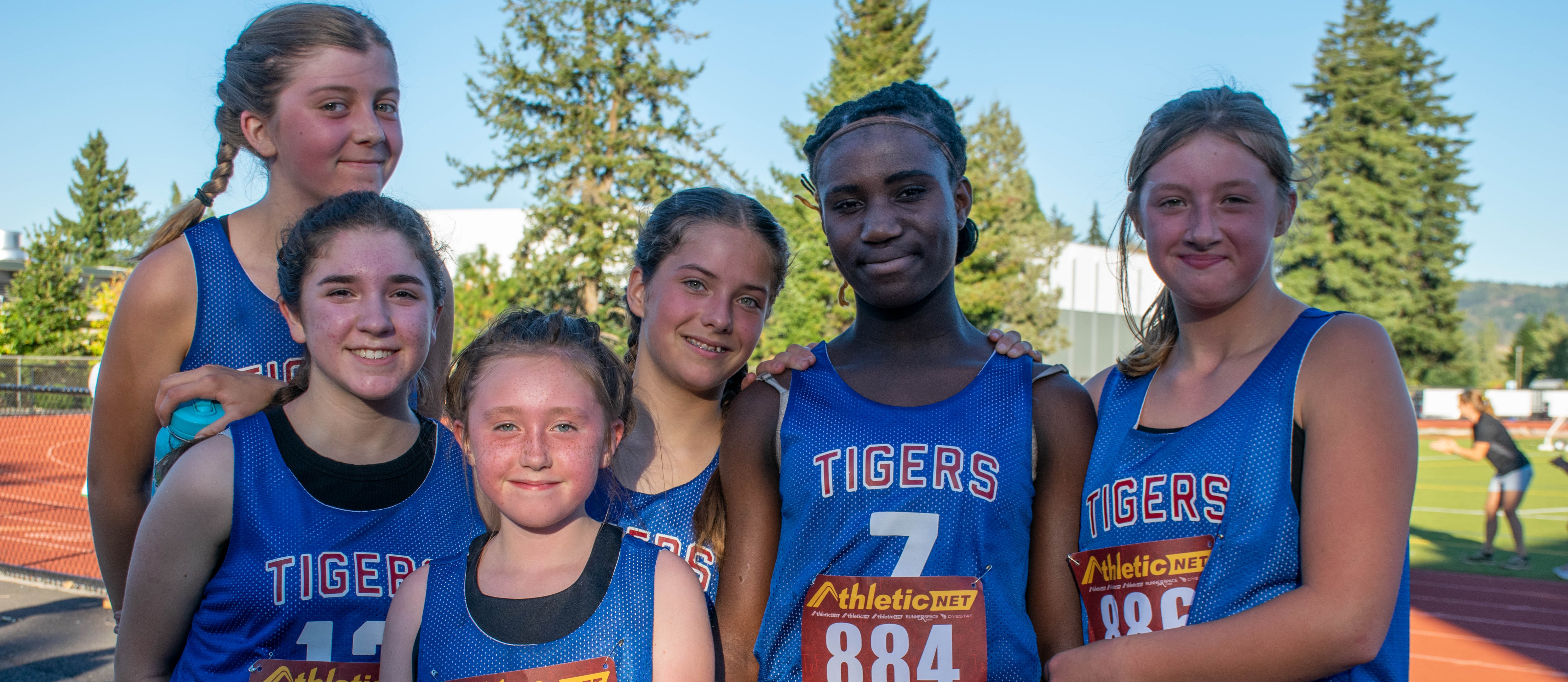 Students smile in cross country uniforms outside