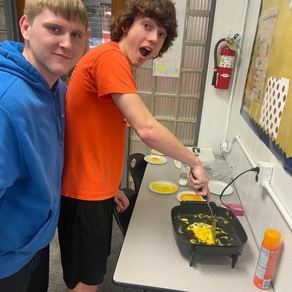 Students making an omelet on a griddle and making funny faces