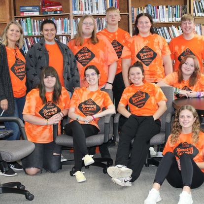 a group of students pose in orange school shirts