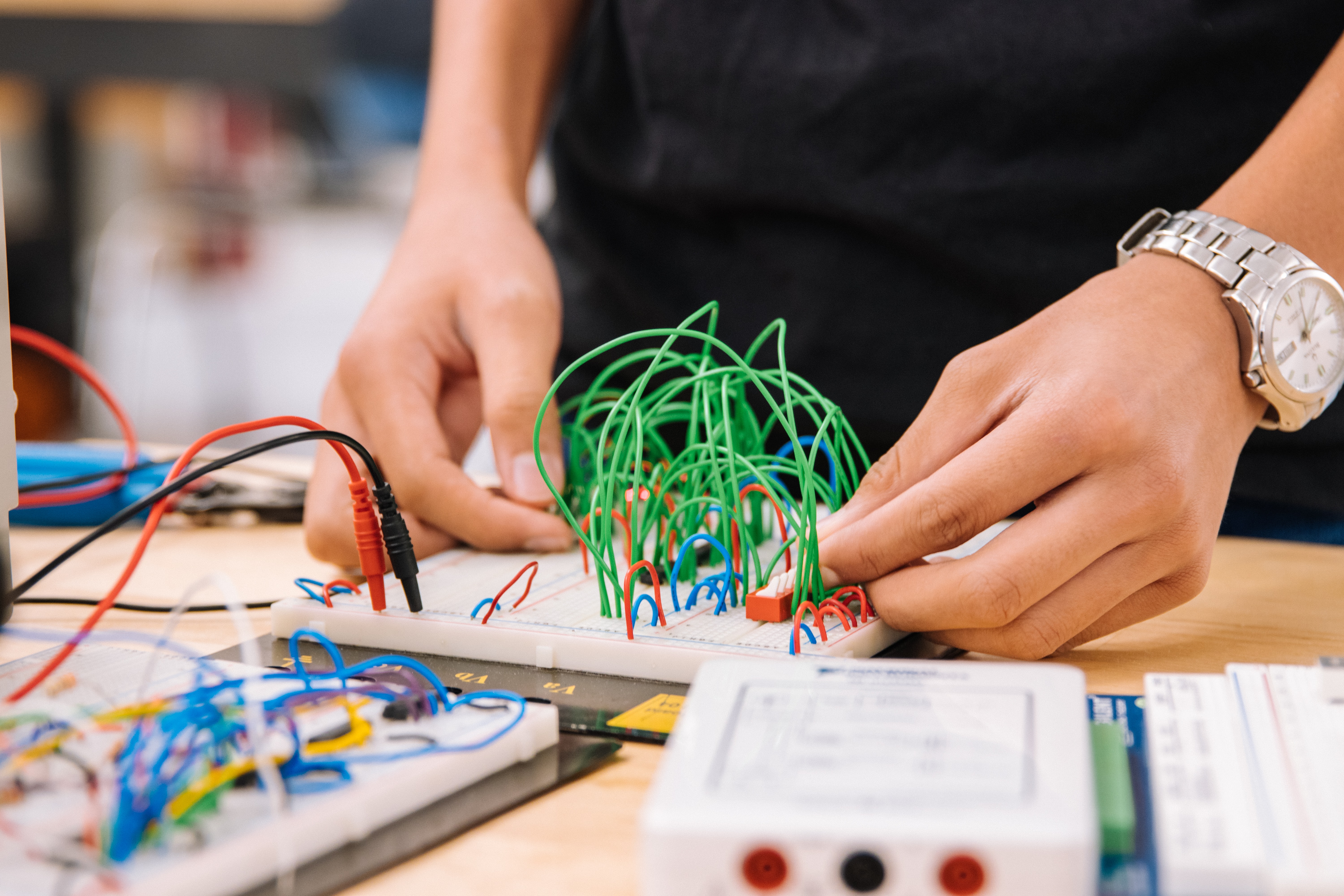 Student's hands working with wires on a table