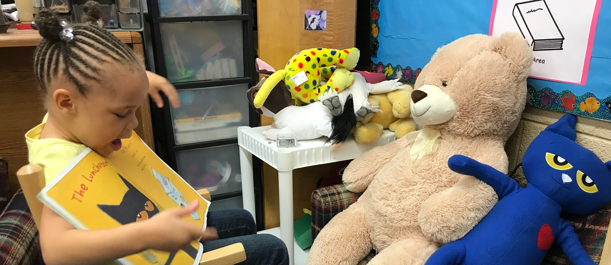 Johnson student reading to a teddy bear and Pete the Cat