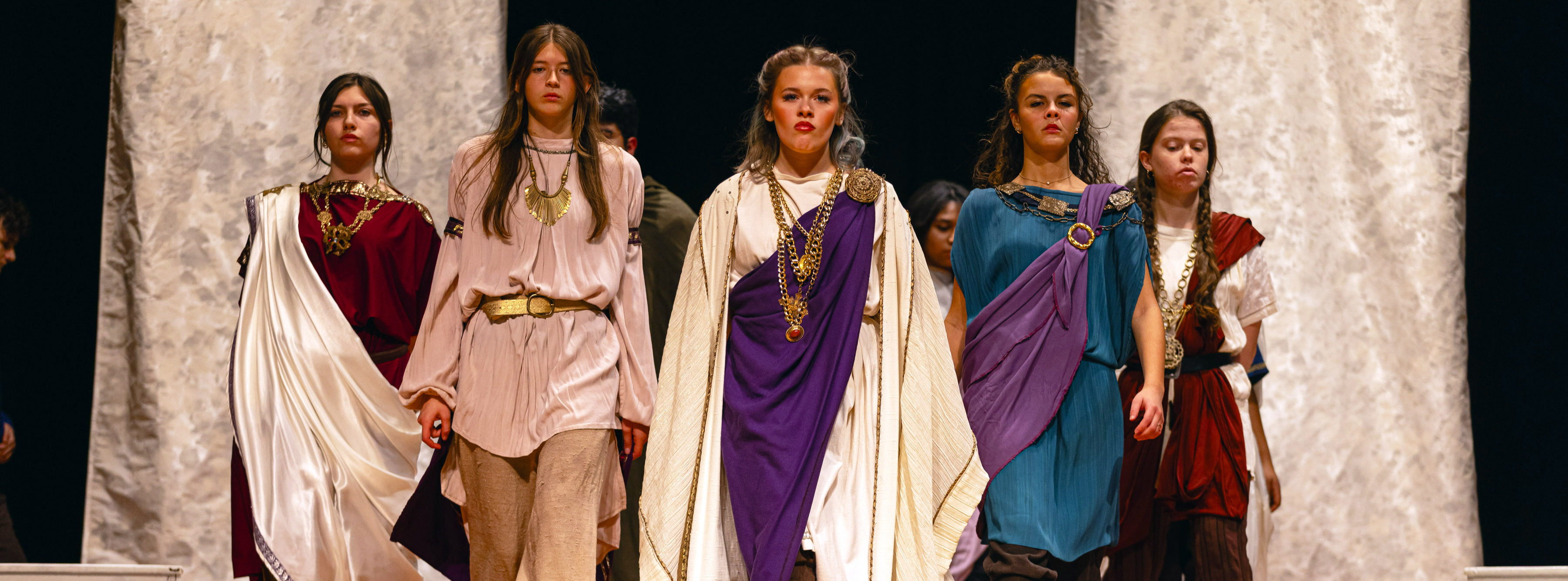 Students dressed in ancient Roman atire strut onto stage in Julius Caesar