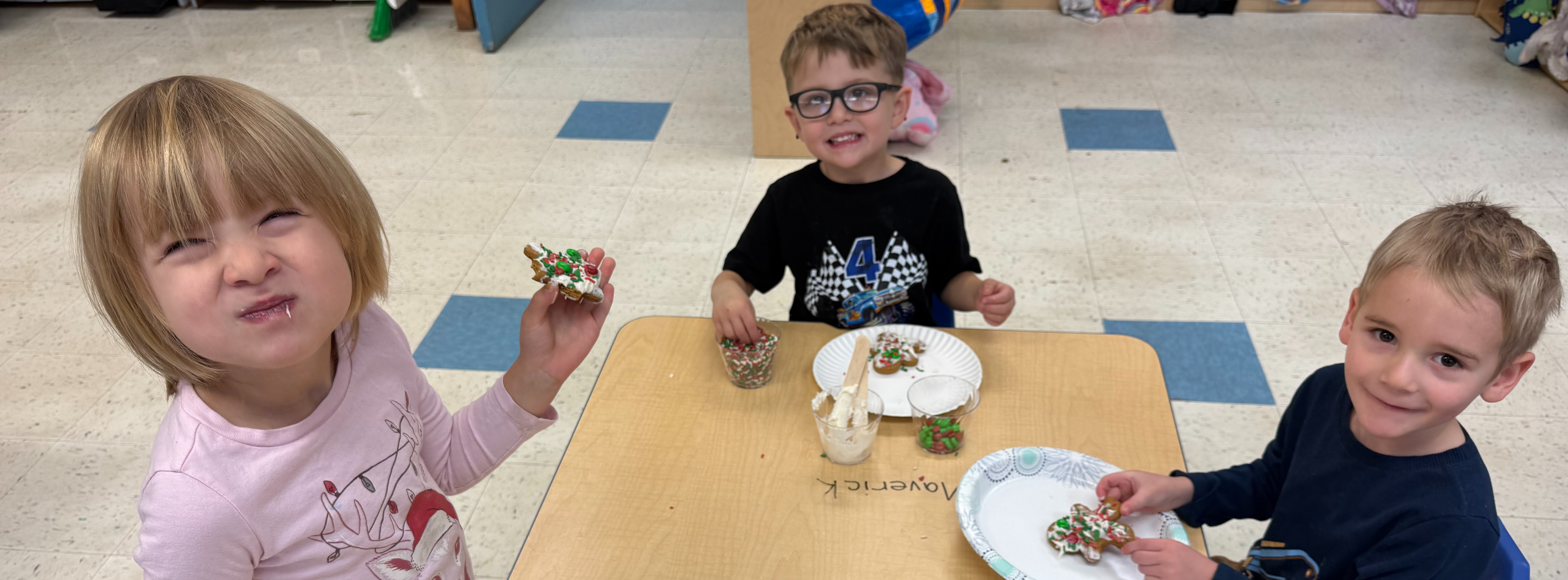 girl and two boys eating gingerbread cookies