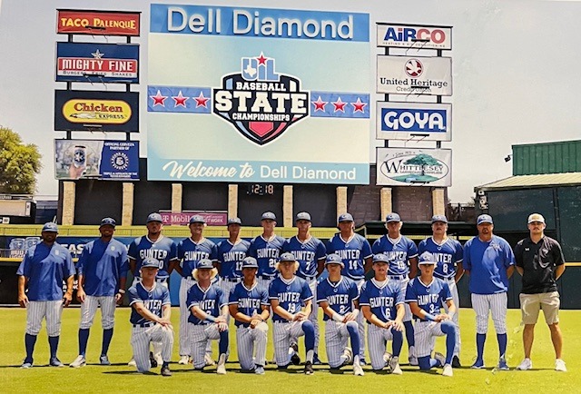 Baseball team in blue and white uniforms posing for a group photo on a field.