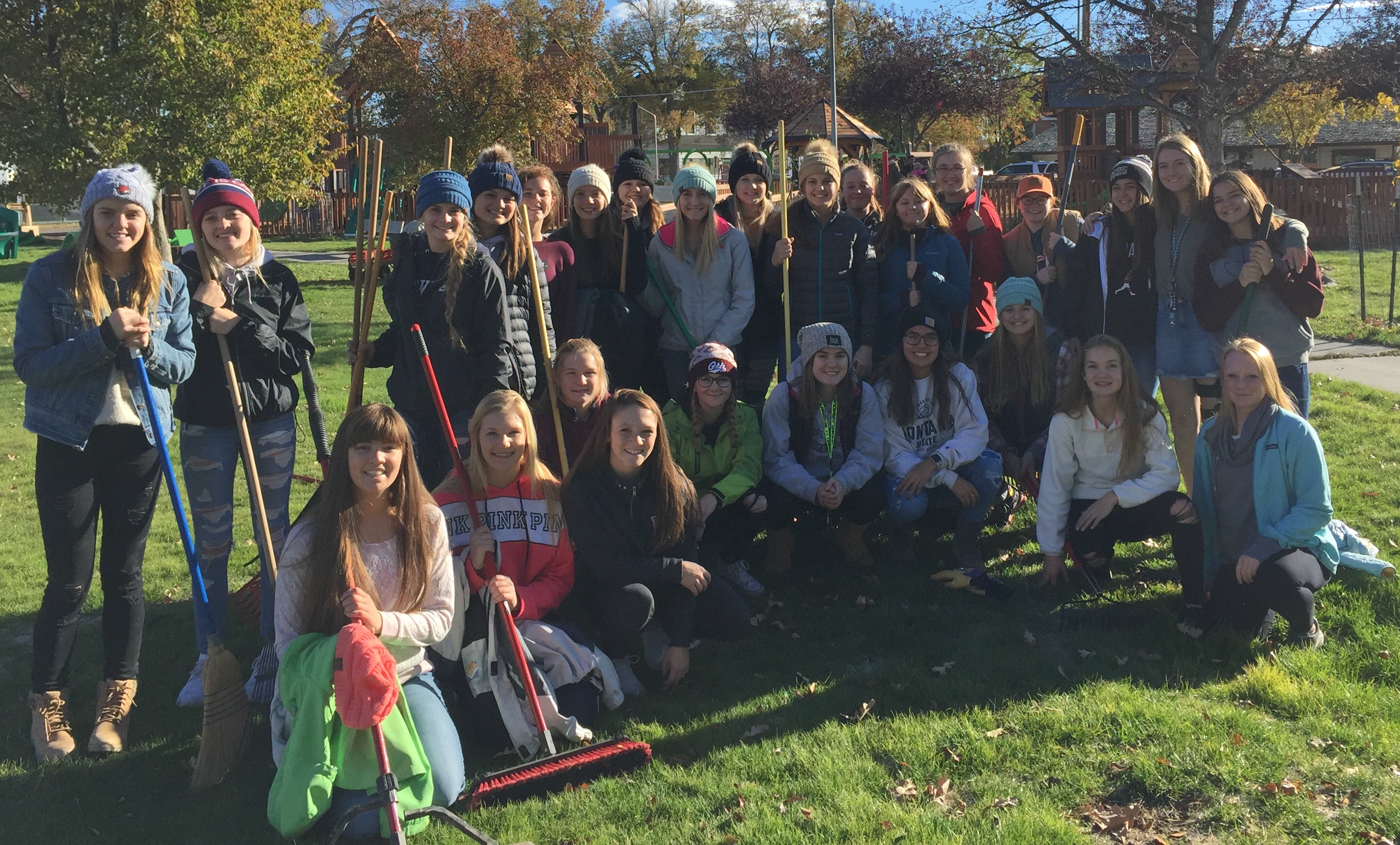 A photo of the volleyball team raking leaves at the Jaycee Park in October 2018