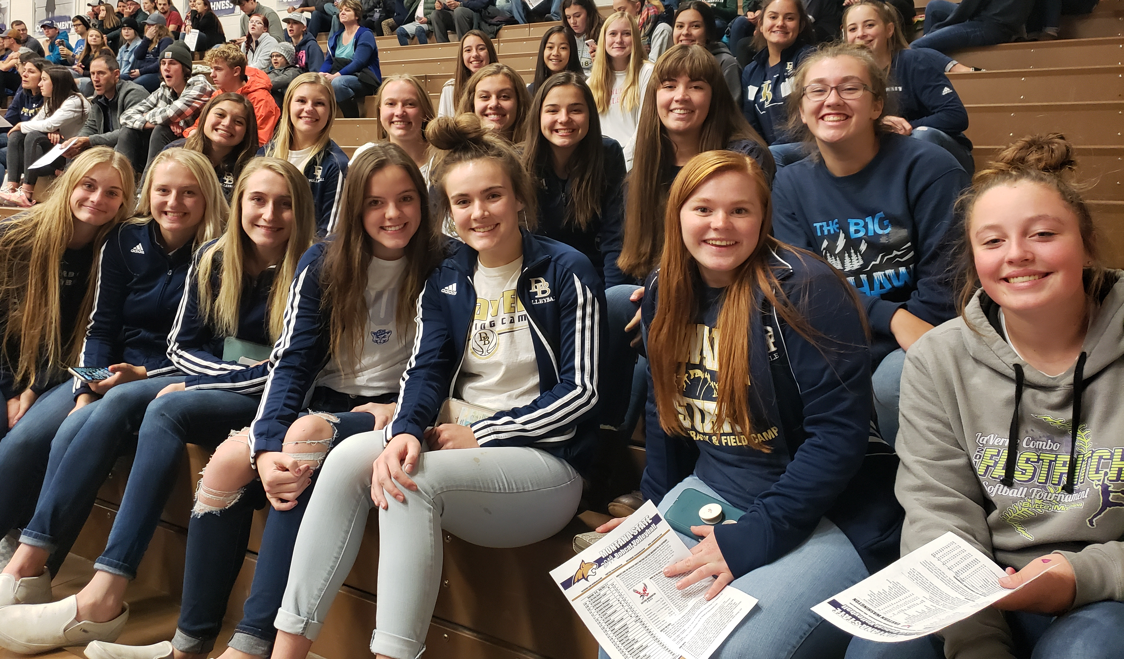 A photo of the volleyball team sitting in the stands enjoying watching some college volleyball