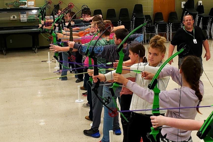 Archery students lined up getting ready to shoot arrows.