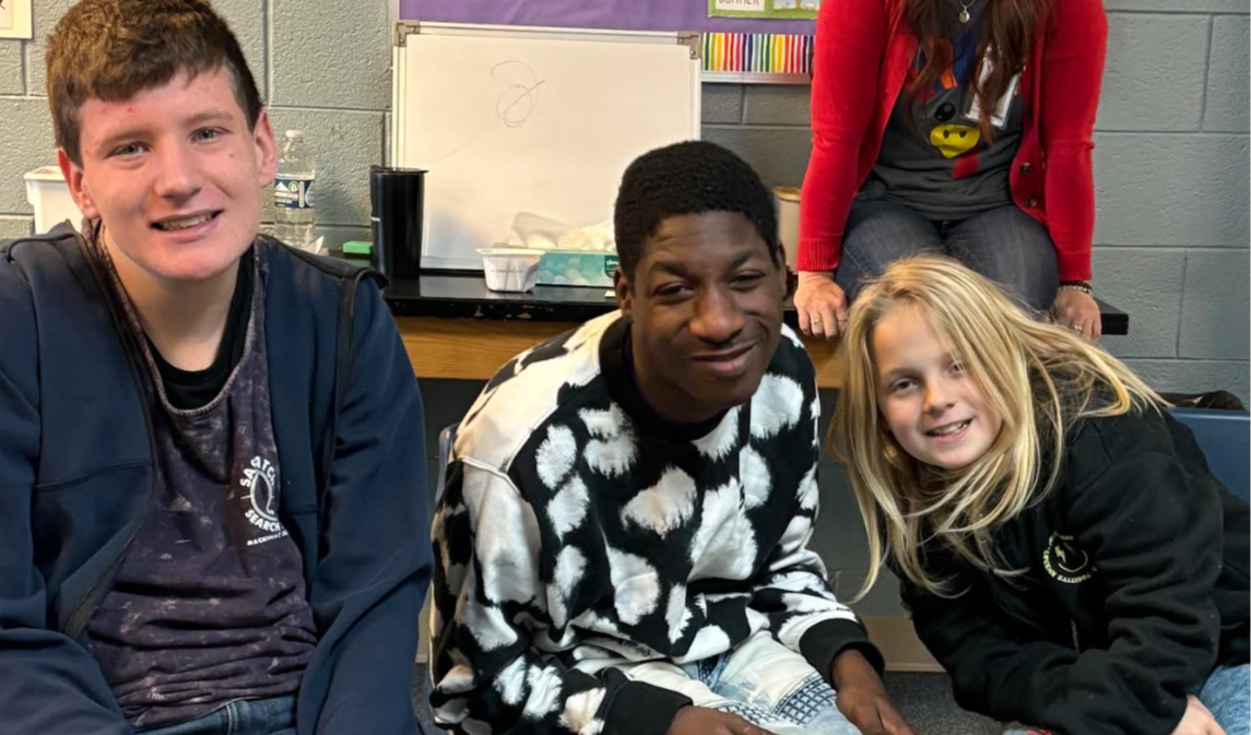 Students sitting in chairs looking at the camera