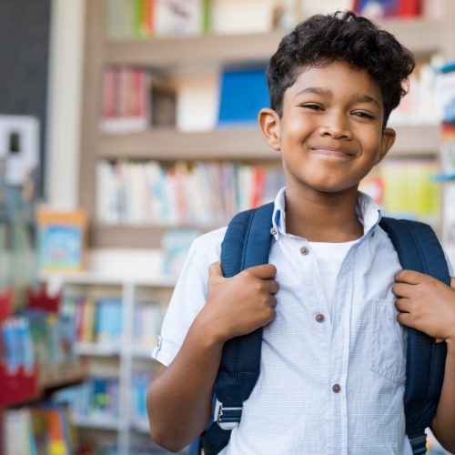 Smiling student wearing a blue backpack in class