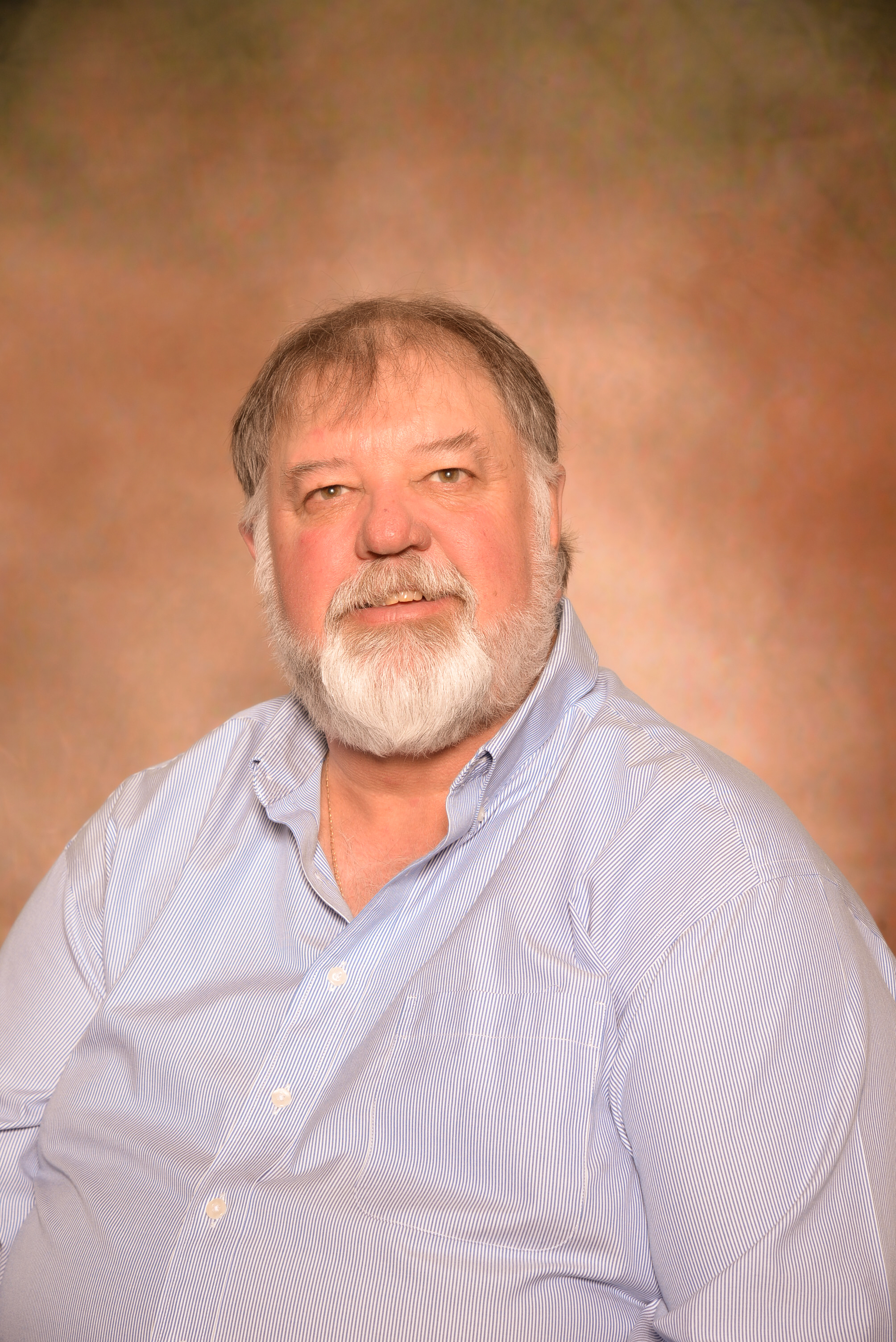 A man in a light blue button down shirt and a beard.
