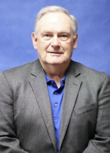 A man in a dark suit jacket and blue shirt.