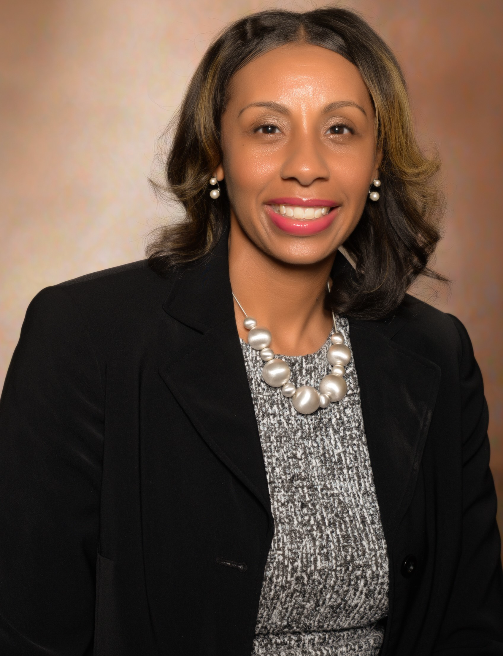 A woman in a dark jacket and wearing a necklace